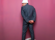 Man standing facing corner of room wearing a dunce cap